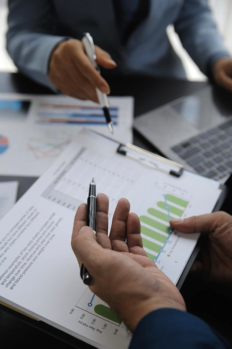 manos de dos hombres con papeles con gráficos